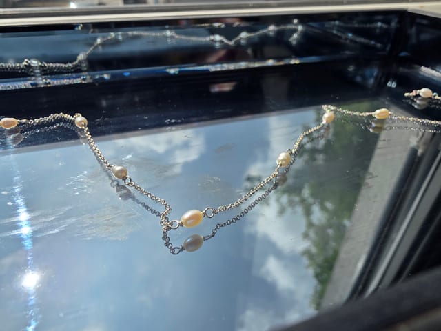 Permanent jewellery - piece, pearl chain on mirror background